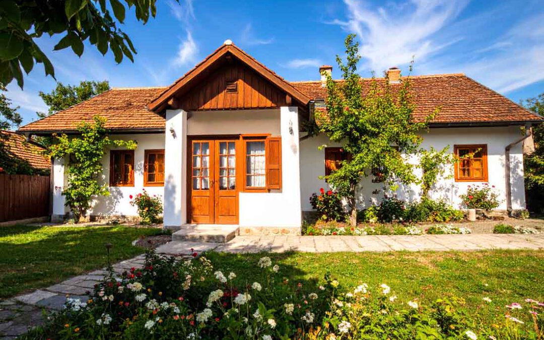 Charmantes ungarisches Landhaus mit weißer Fassade, braunem Ziegeldach und blühendem Garten symbolisiert einen sonnigen Tag in Csepreg, Komitat Vas