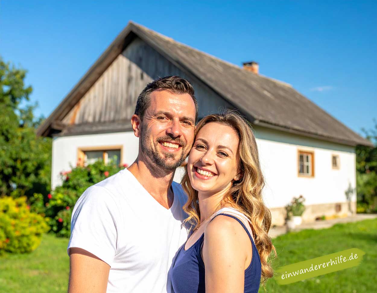 Junges Paar freut sich über günstiges Haus mit großem Grundstück in Vas, sonniger Sommertag.