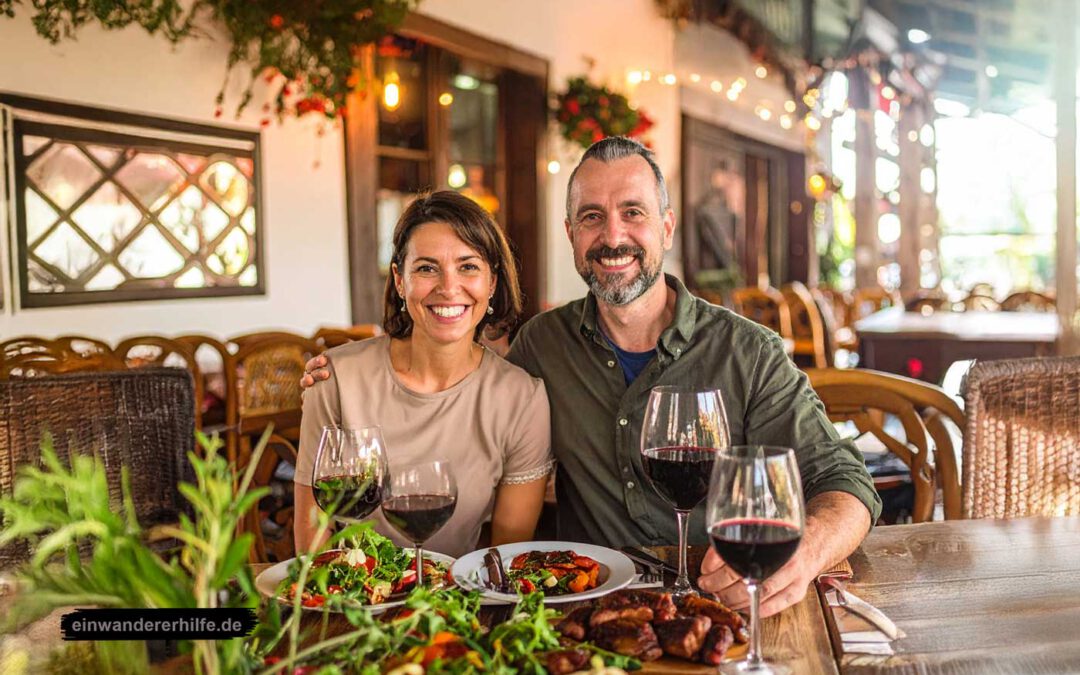 Szigetvar - Ein lächelndes Paar sitzt an einem gedeckten Tisch mit Wein und traditionellen Speisen in gemütlicher Atmosphäre. Symbolbild glückliche Expats.